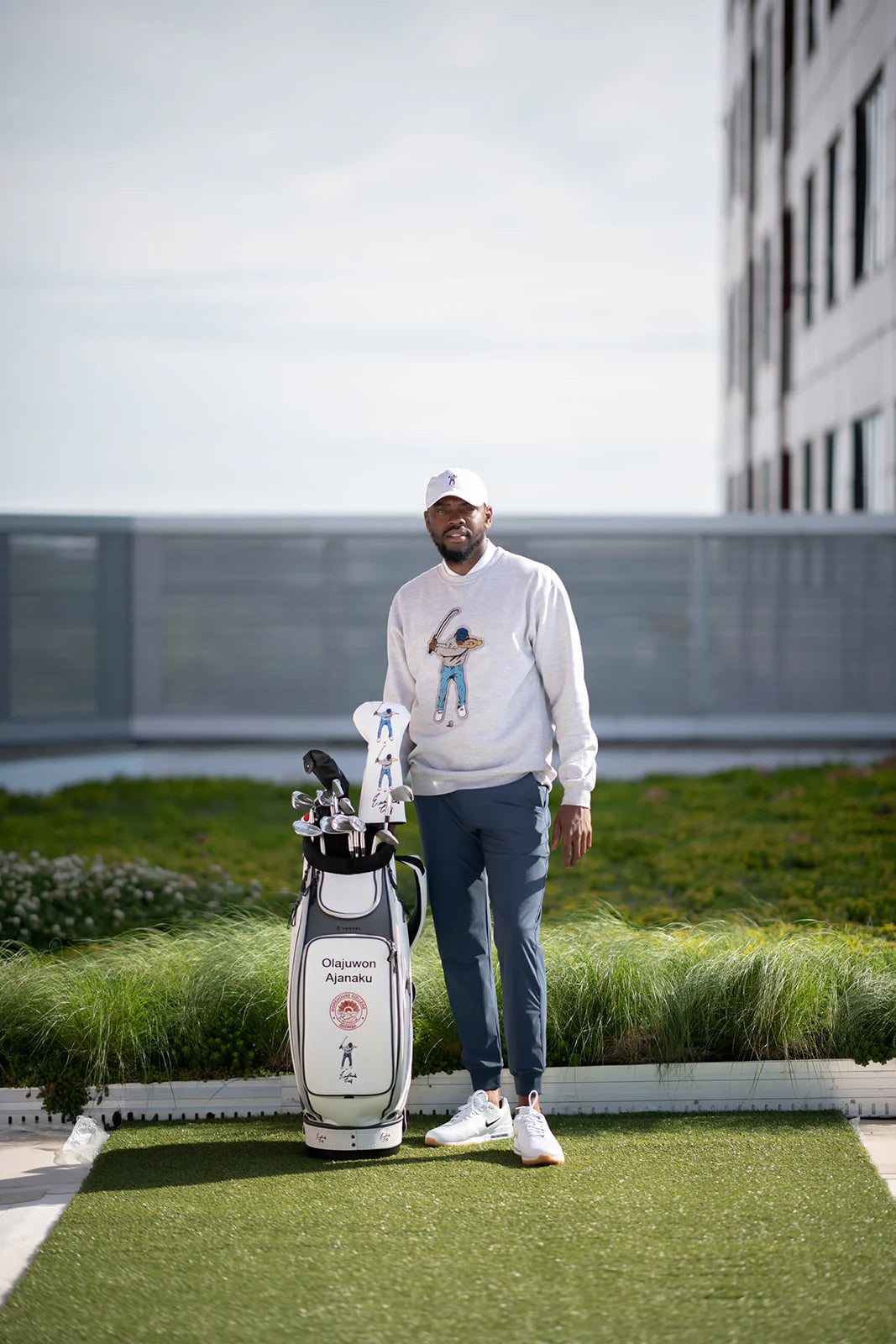 Olajuwon Ajanaku 穿著繡有 Swingman 小人的運動衫,站在寫有自己名字的白色球袋旁