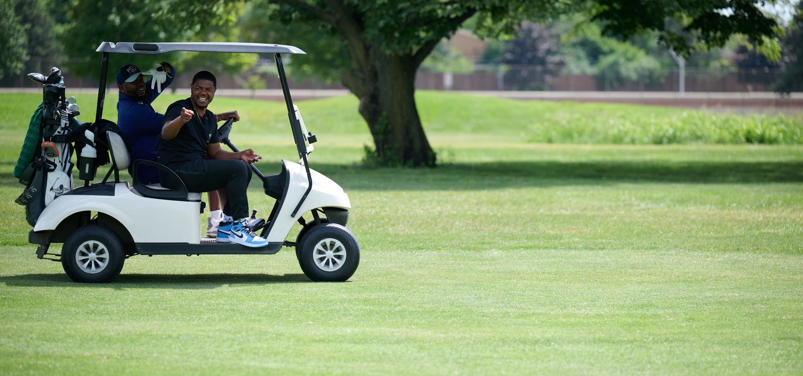 Eastside Golf 兩位創辦人坐在球車上,在球道邊笑著