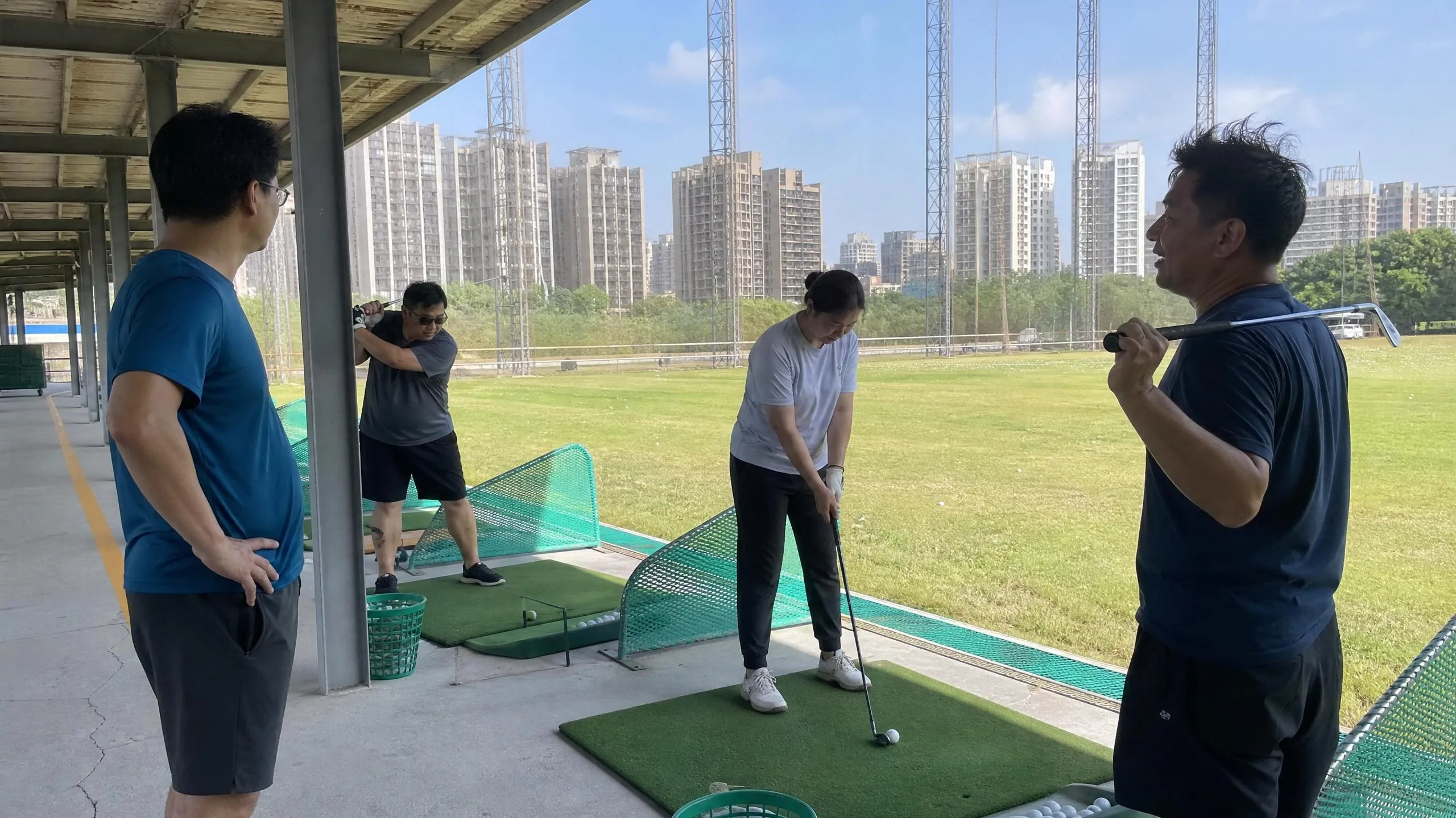 台灣戶外練習場的高爾夫教練課：三名學員各自練習，動作各不相同